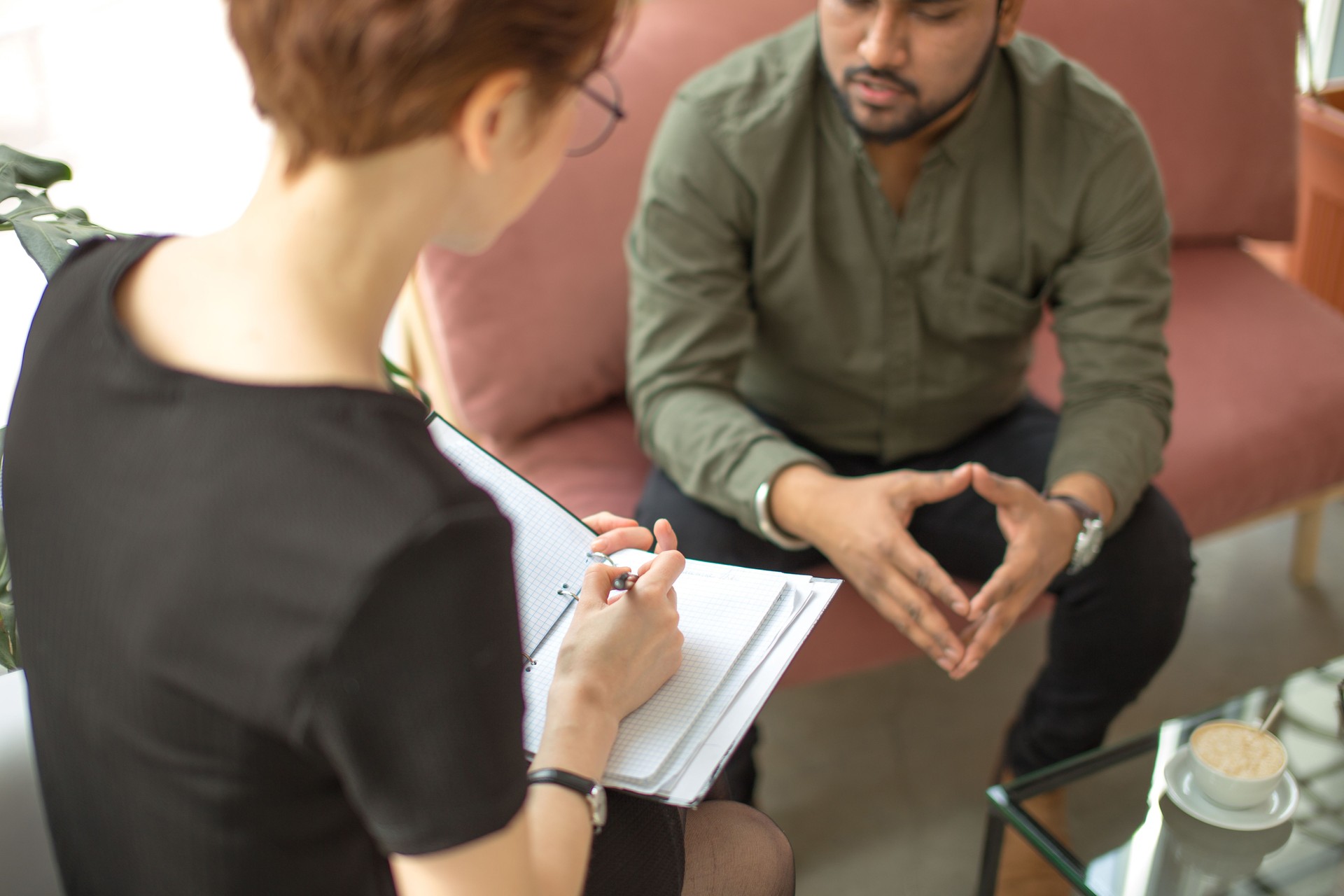 psychologist consulting indian man, writing notes during psychological therapy session
