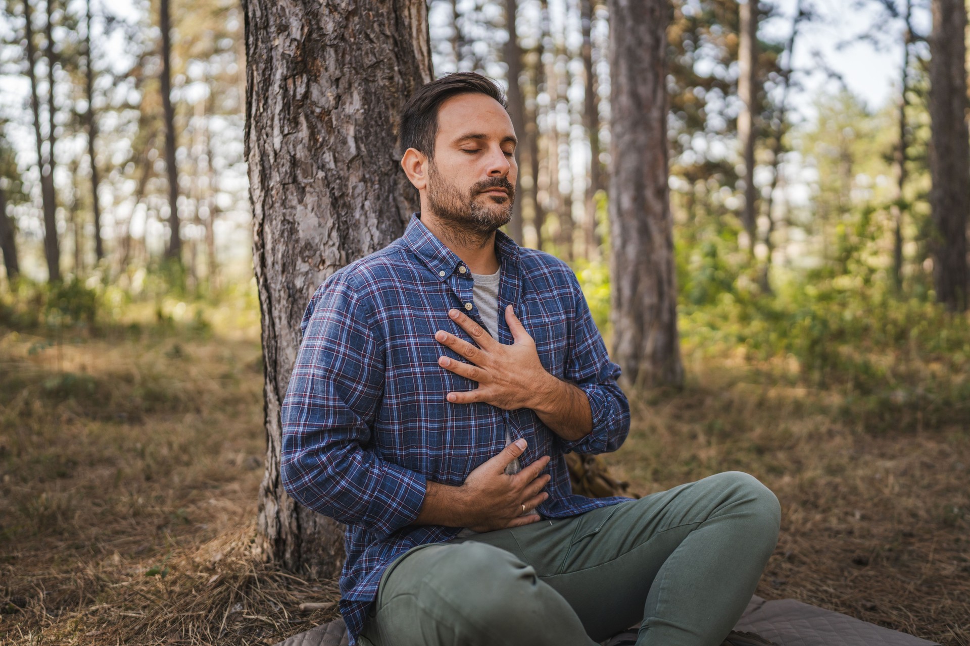 Adult man camper practice meditation and breath exercise in front tree
